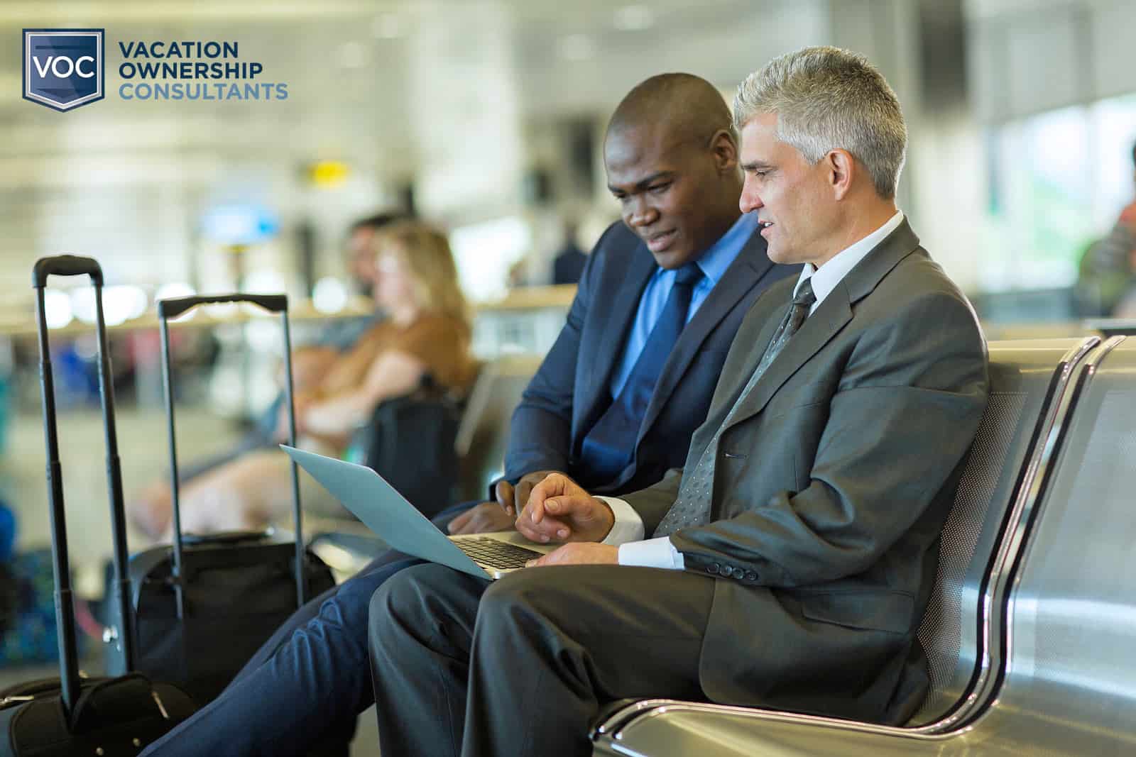 two-men-looking-at-timeshare-contract-and-discussing-travel-club-membership-at-airport-while-waiting-for-flight