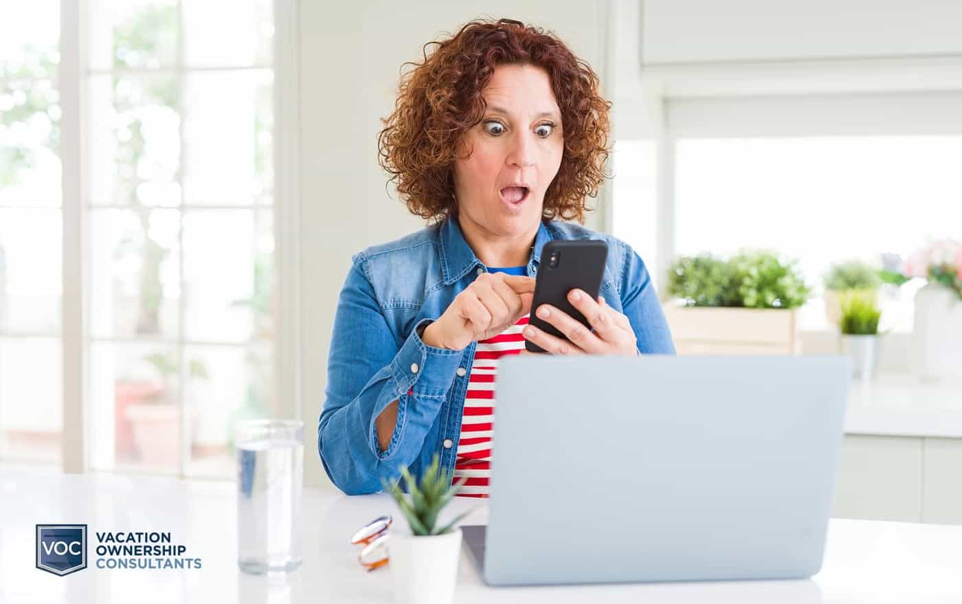 woman-looking-at-phone-while-on-computer-researching-resort-relief-programs-online-toget-rid-of-contractual-agreements-and-she-found-something-surprising