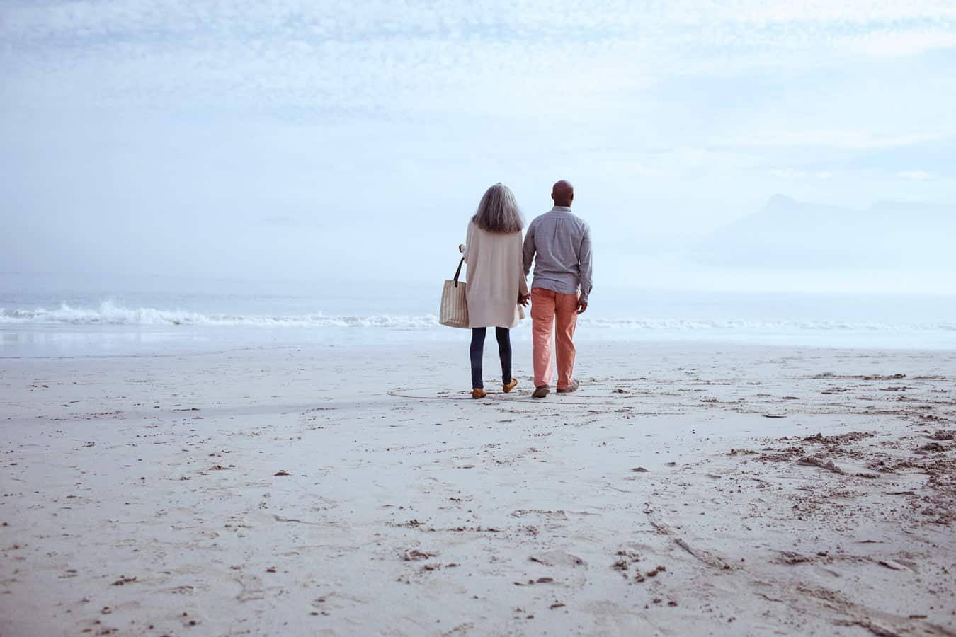 older-couple-walking-on-beach-in-distance-glad-they-got-out-of-their-timeshare-contract-instead-of-filing-bankruptcy
