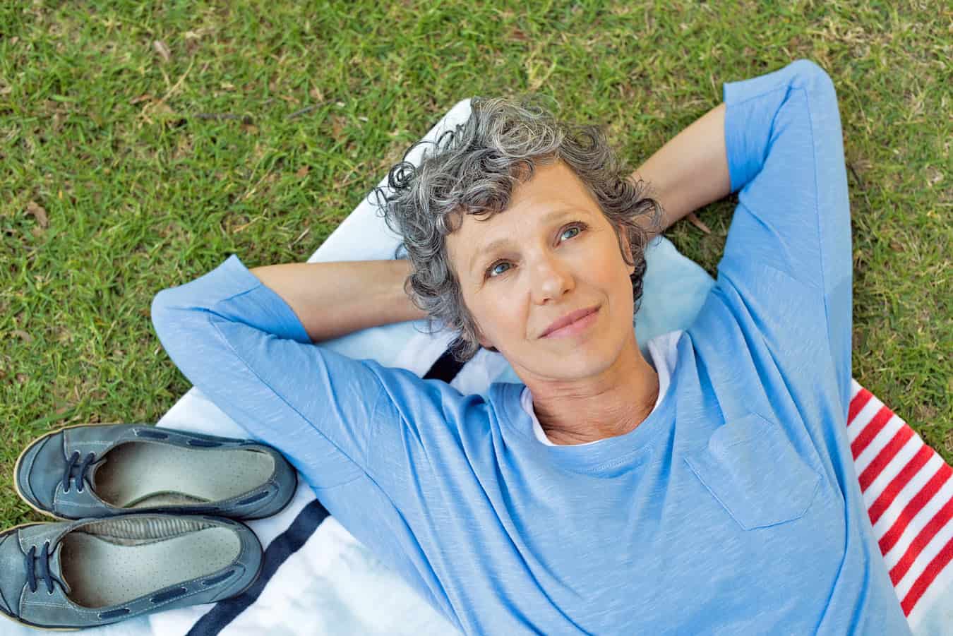 woman-gazing-at-sky-on-back-on-grass-thinking-about-what-to-do-with-her-vacation-ownership-during-picnic