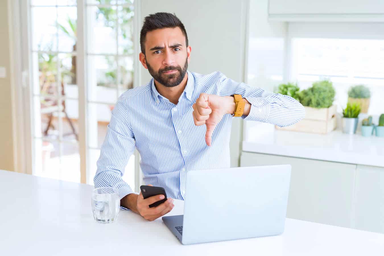 man-with-cell-phone-in-hand-looking-to-call-timeshare-company-while-on-computer-to-settle-it