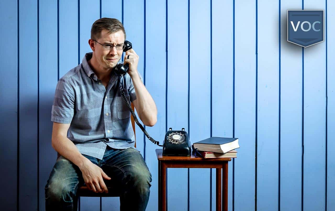 middle-aged-man-crying-on-rotary-phone-with-blue-wood-slat-background-arguing-about-timeshare-exit-investment