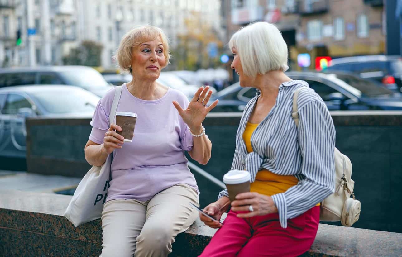 aging-white-women-chatting-downtown-about-fraudulent-timeshare-exit-marketplace-over-coffee-paradigm-shift-by-friend