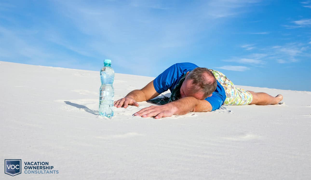 dehydrated-man-in-blue-shirt-in-desert-reaching-for-water-but-unable-to-grab-it-before-expiring-in-desert-sand-blue-sky-voc