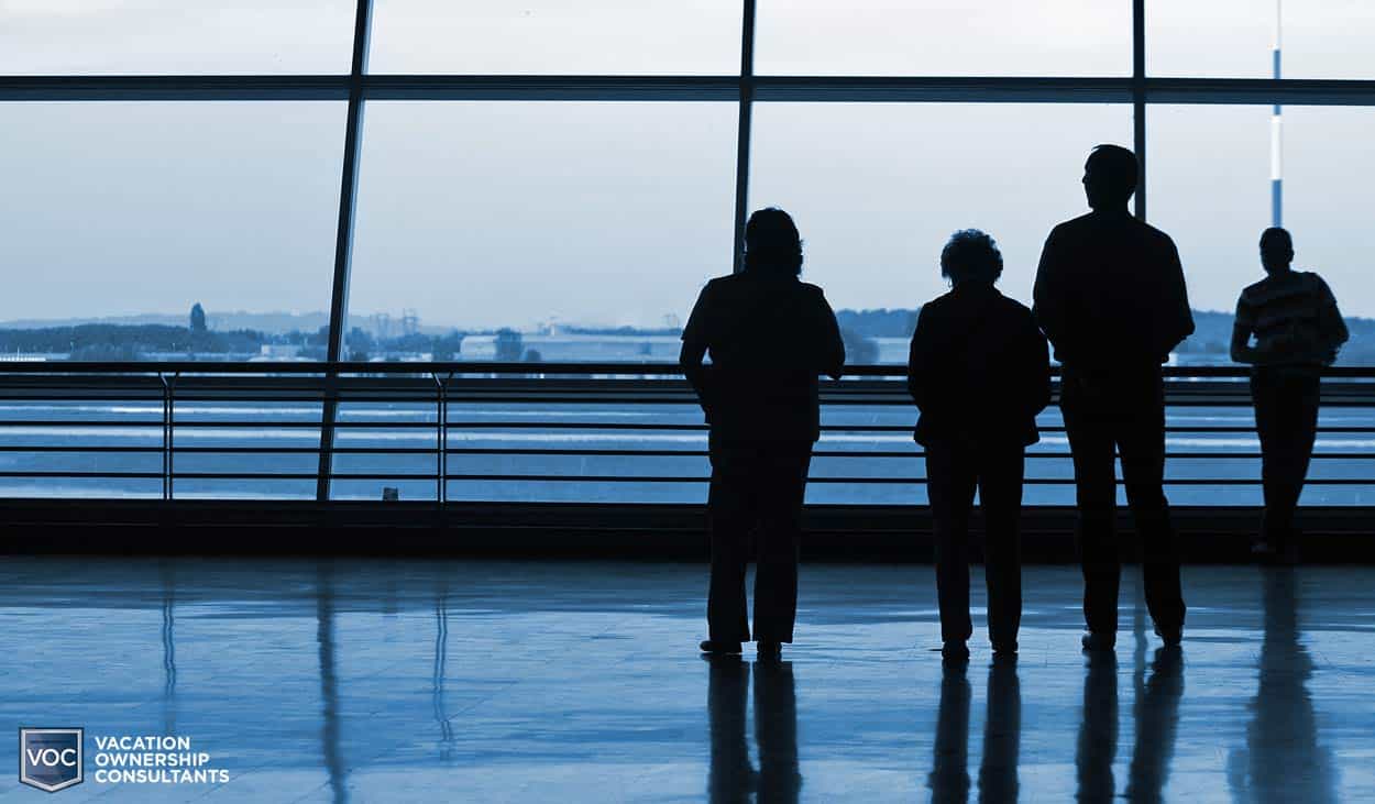 group-of-travelers-standing-at-airport-window-waiting-for-airplane-to-take-them-back-to-america