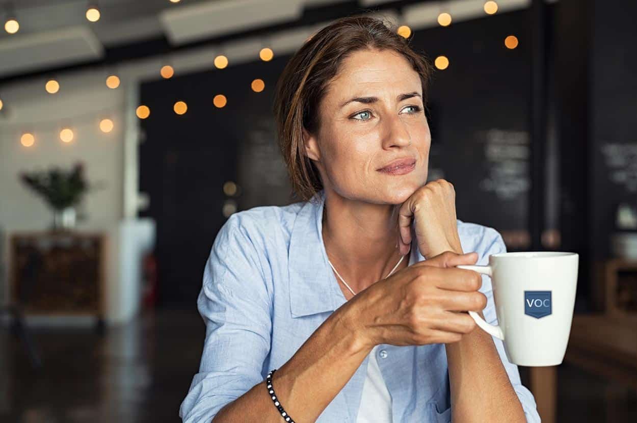 woman-semi-smiling-sitting-in-coffee-shop-with-voc-mug-thinking-about-better-timeshare-experience