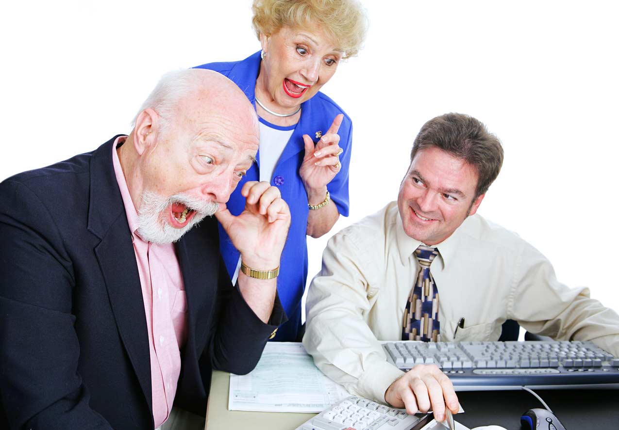 grandma-over-grandpas-shoulder-reaffirming-his-purchase-decision-with-sleezy-timeshare-salesman-punching-numbers-at-desk-with-greedy-grin-predator-of-elderly