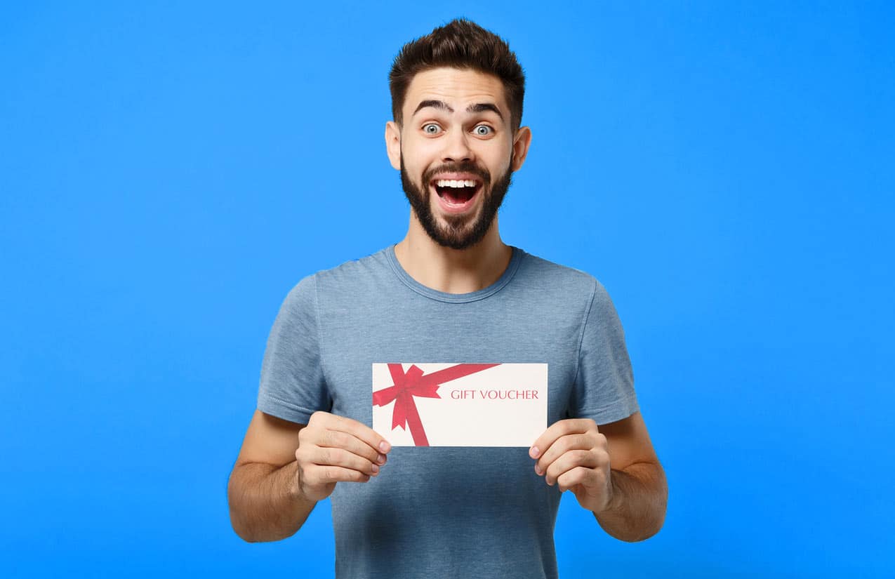 gift-certificate-or-voucher-wrapped-in-fake-bow-on-paper-held-by-cheerful-younger-gentleman-seemingly-excited-about-redeemable-gift-towards-bought-timeshare-product