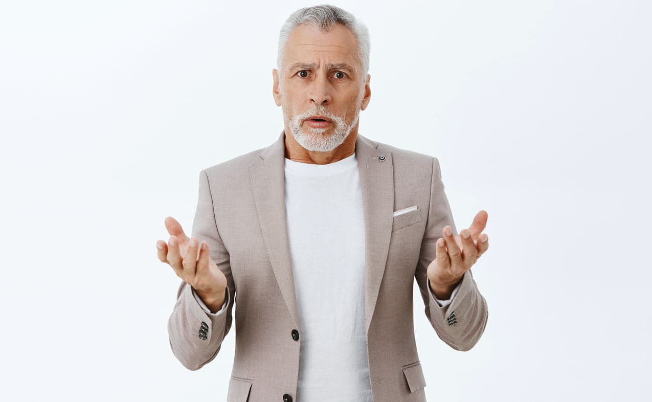 clueless-looking-man-in-sport-coat-arms-raised-grey-hair-spanish-goatee-vacation-owner-white-backdrop