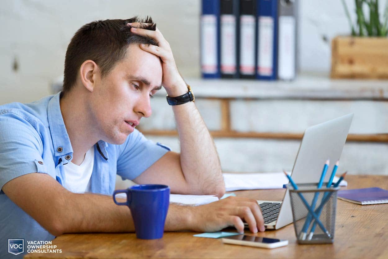 younger-man-browsing-internet-tired-of-looking-at-options-for-timeshare-exit-teams-on-computer