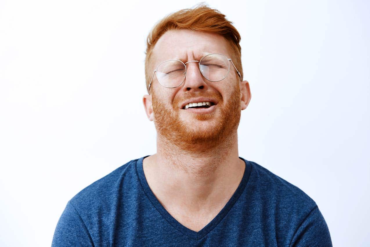 whining-man-ginger-in-glasses-disappointed-with-regretful-timeshare-purchase-to-destination-city-white-background-blue-shirt