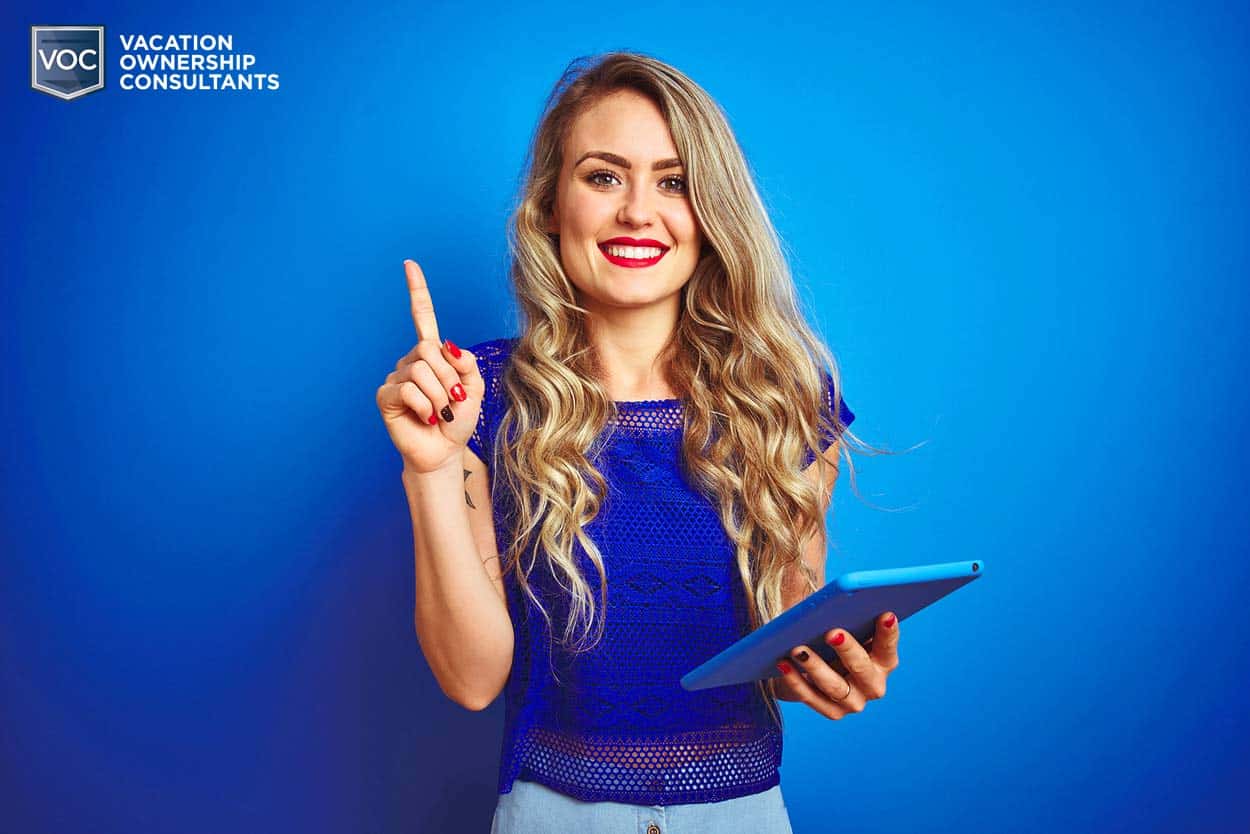 blue-background-and-blouse-blonde-with-gesture-of-idea-and-blue-tablet-smiling-about-canceling-timeshare-mortgage