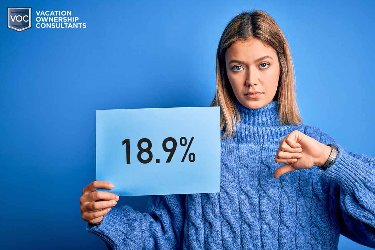 18.9%-on-blue-paper-held-by-unhappy-fractional-owner-young-woman-in-sweater-thumbs-down-to-purchase-loan-interest-rates-thought-would-be-lower-or-refinance
