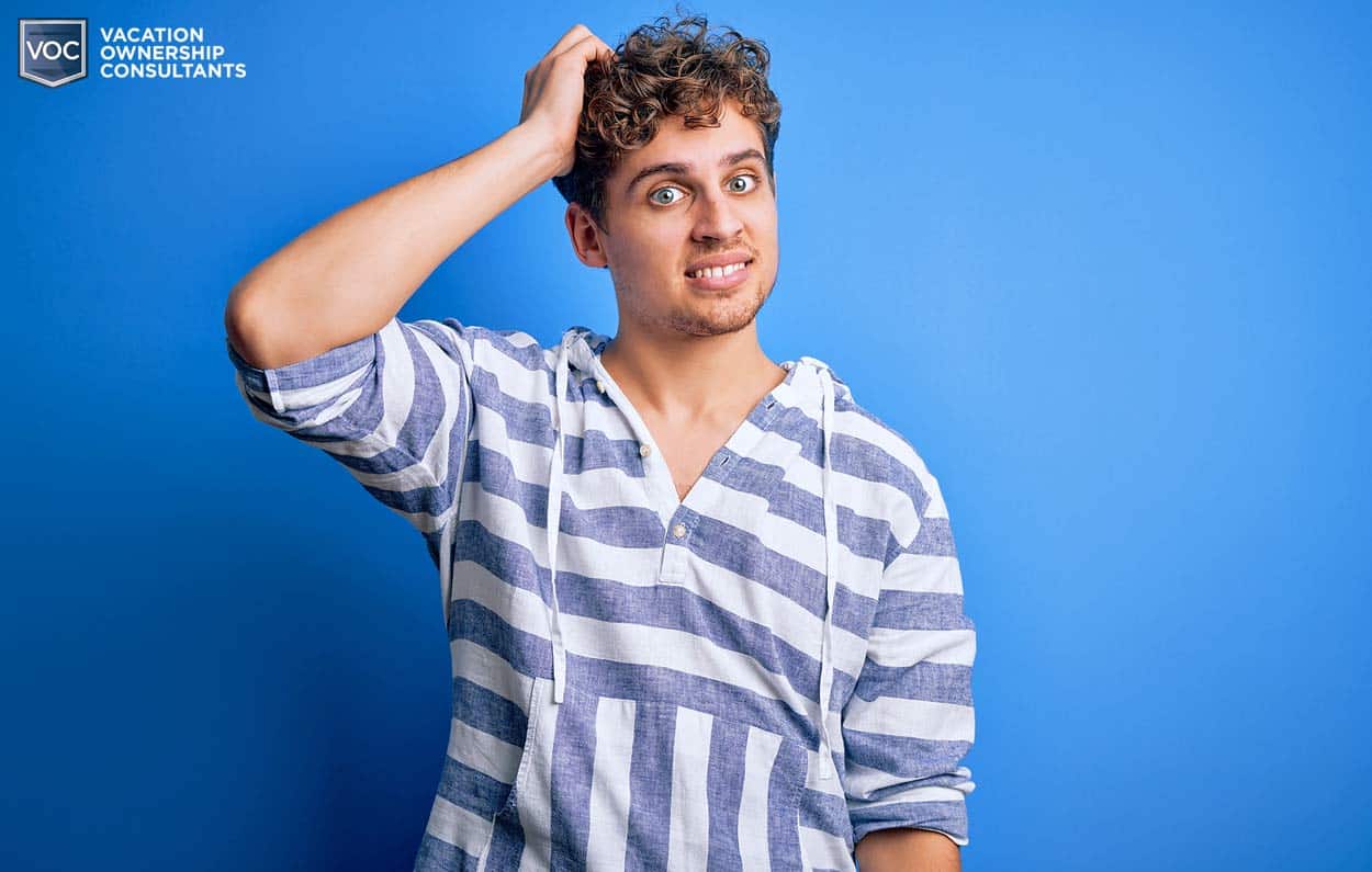 blue-background-striped-shirt-hooded-scratching-curly-head-confused-about-sales-pitch-alone-uninformed