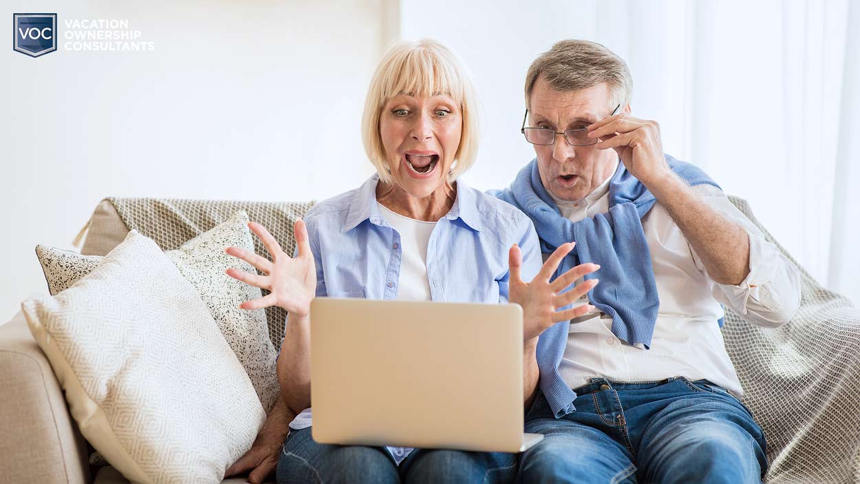 older-couple-white-on-couch-enthusiastic-over-computer-screen-online-help-with-timeshare