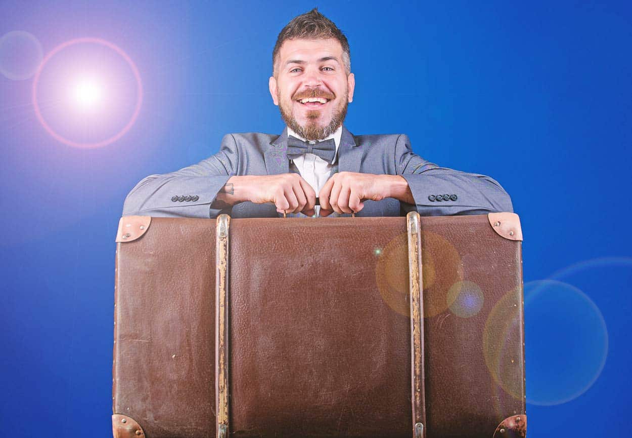 blue-background-light-lens-flare-man-in-suit-with-huge-suitcase-weighted-down-for-trip-with-unecessary-timeshare-baggage