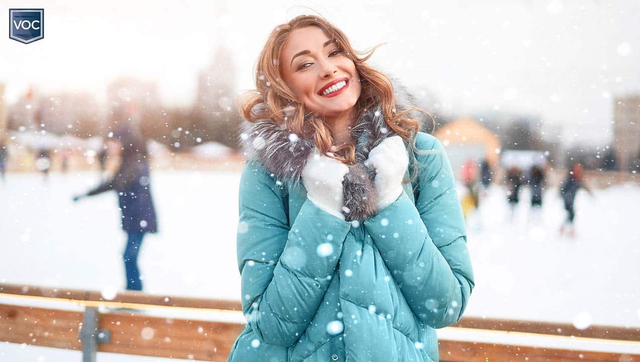 gorgeous-young-woman-in-teal-jacket-smiling-red-lipstick-during-snowfall-at-outdoor-skating-ring-for-christmas-festivities-during-holiday-lockdowns