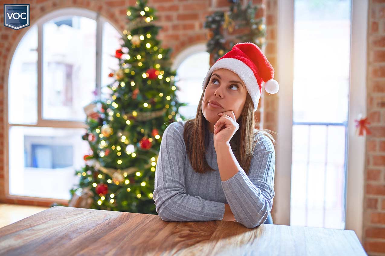wishful-thinking-during-christmas-holiday-season-vacationing-owner-thinking-about-breaking-timeshare-contract-at-table-tree-lights-behind-her
