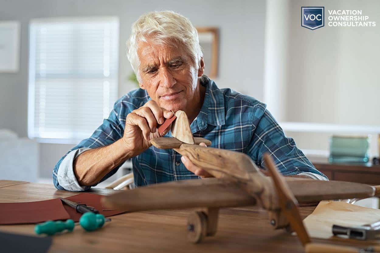 older gentleman putting together wooden airplane for decor project selling online for revenue to pay off timeshare dues