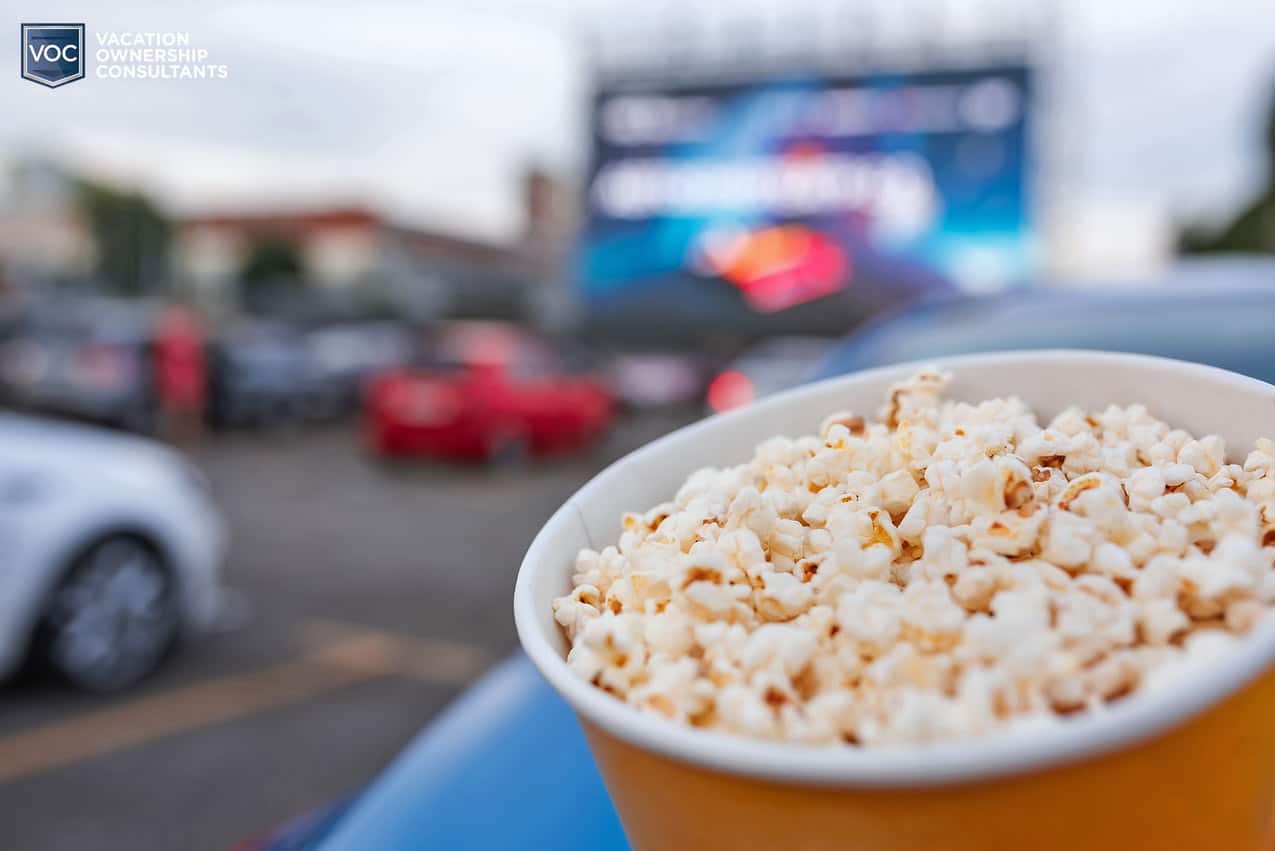 big-paper-bowl-popcorn-outside-movie-screen-with-cars-drive-in-experience-instead-of-imax-for-covid-19-entertainment-2021