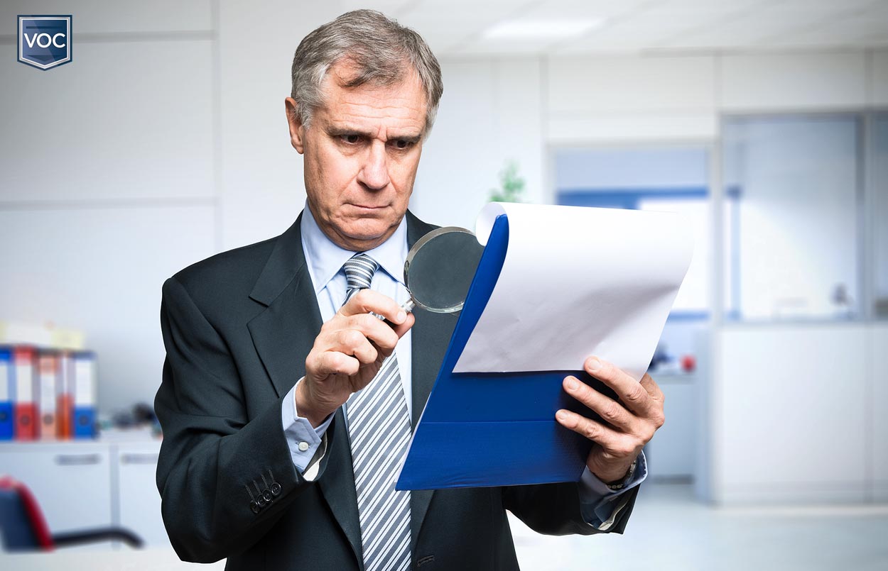 business man fired looking at details on paper contract with magnifying glass to uncover fine print of timeshare obligations for special assessments