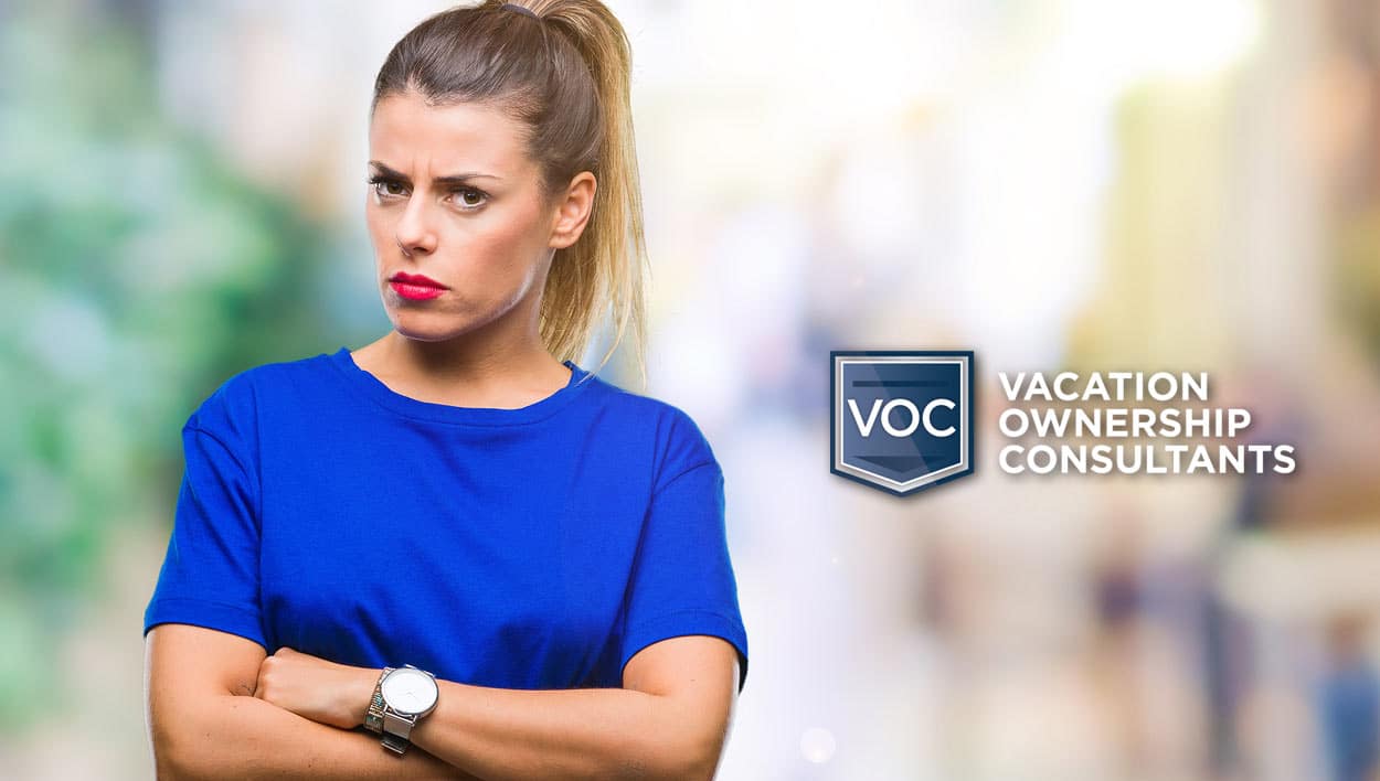 crossed woman standing in city blurry background bright blue shirt red lipstick hair back upset with cnbc article about timeshare resale