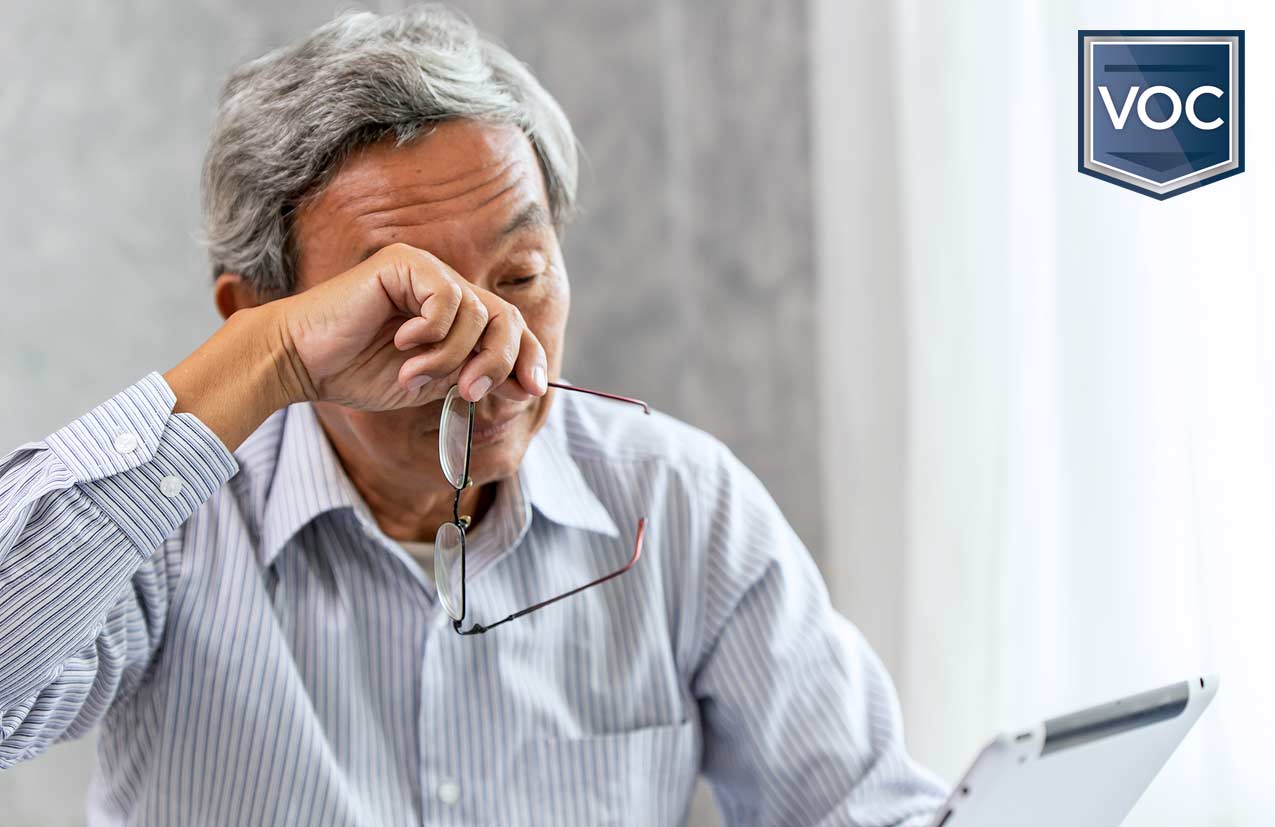 asian man wiping brow possibly tear as he reviews timeshare transaction when he can't even travel during 2021 because of global choas