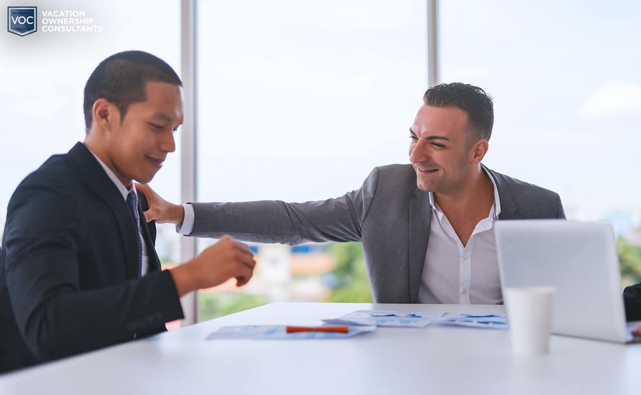 salesman's arm on shoulder of consumer target during pitch trying to talk them in to signing agreement for timeshare ownership against wishes pandering