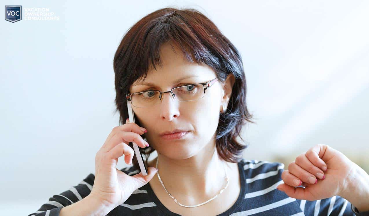 confused looking middle aged retired woman on phone with timeshare company telling her she cannot make up for losses of 2020 covid lockdowns at resorts